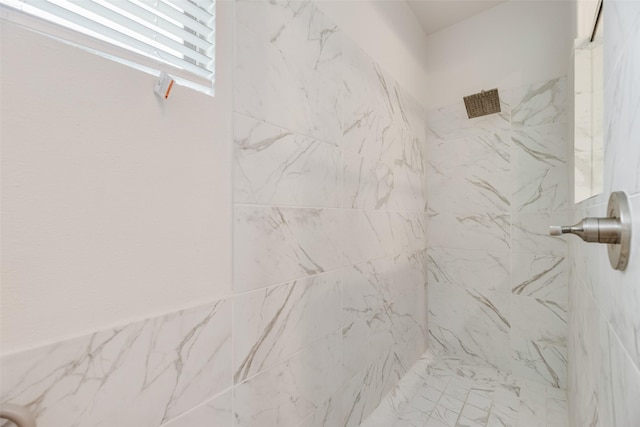 interior details featuring a marble finish shower