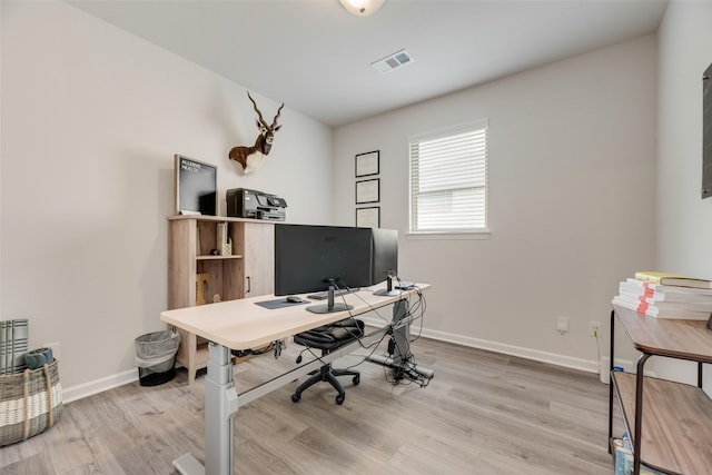 office area with light wood-type flooring, baseboards, and visible vents