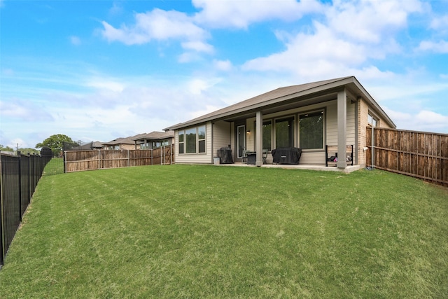 rear view of property with a yard, a patio, and a fenced backyard