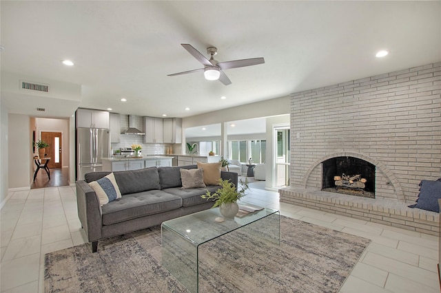 living area with ceiling fan, a brick fireplace, recessed lighting, light tile patterned floors, and visible vents