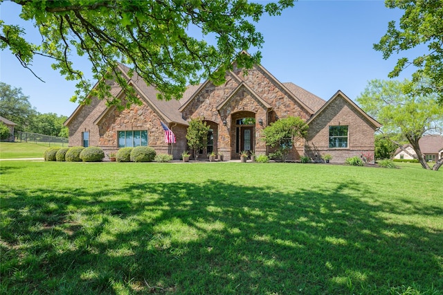 view of front of home with stone siding, a front lawn, and fence