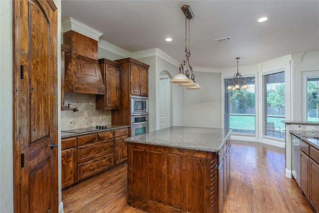kitchen with a center island, wood finished floors, decorative backsplash, arched walkways, and appliances with stainless steel finishes