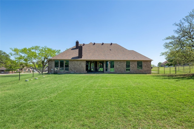 back of property featuring a yard, a chimney, and a fenced backyard