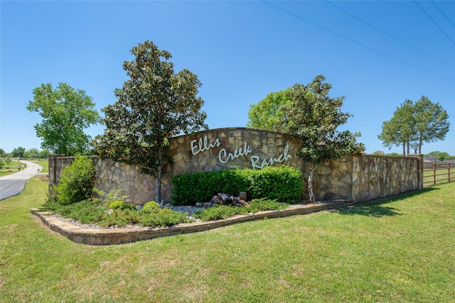 community / neighborhood sign featuring a lawn and fence