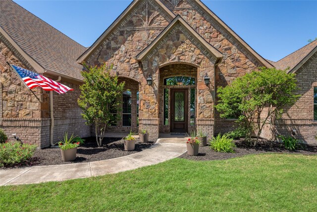 100 Meadow Arbor Dr, Weatherford, TX 76085 - property entrance with a lawn, brick siding, stone siding, and a shingled roof