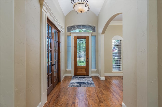 foyer entrance with french doors, arched walkways, baseboards, lofted ceiling, and wood finished floors