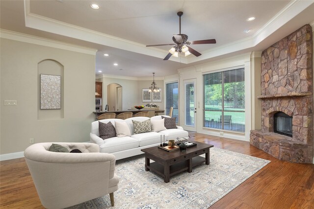100 Meadow Arbor Dr, Weatherford, TX 76085 - living room featuring a tray ceiling, a stone fireplace, a ceiling fan, a chandelier, and crown molding