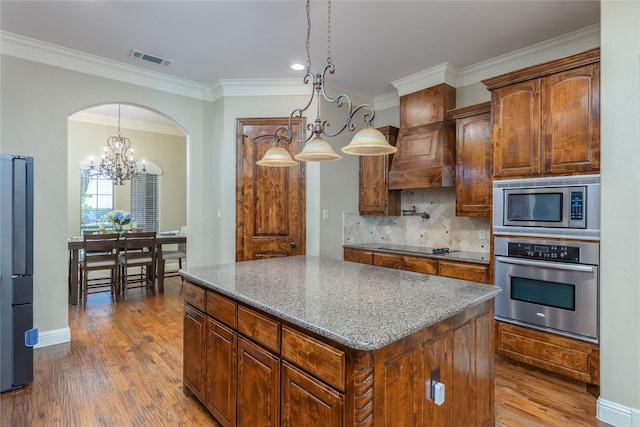 dining room featuring wood finished floors, arched walkways, baseboards, ornamental molding, and visible vents