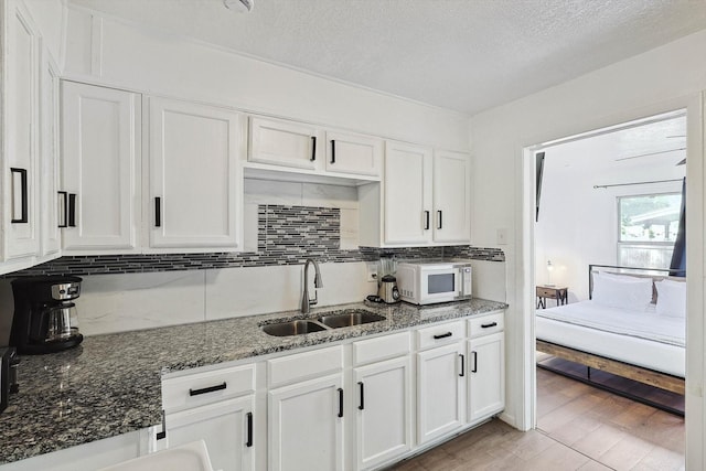 kitchen featuring white cabinetry, tasteful backsplash, a sink, and white microwave