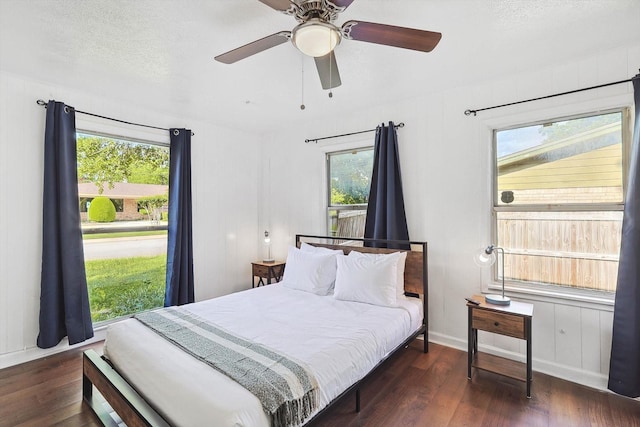 bedroom with baseboards, a ceiling fan, wood finished floors, and multiple windows