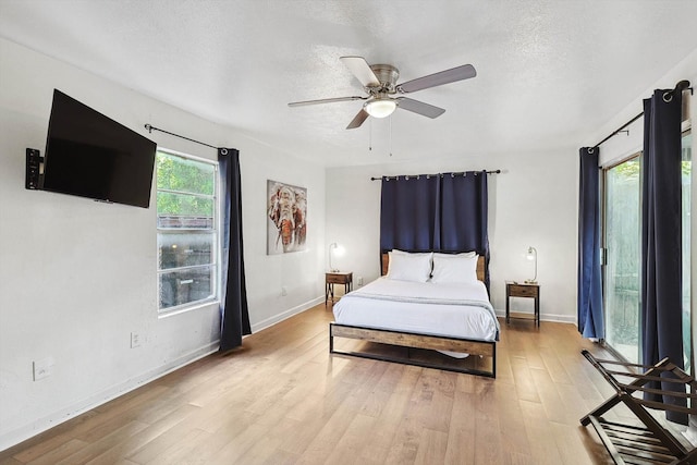 bedroom with ceiling fan, baseboards, wood finished floors, and a textured ceiling