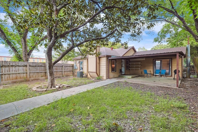 back of property featuring a lawn, fence, cooling unit, and a shingled roof