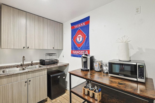 kitchen with stainless steel microwave, light wood-type flooring, and a sink