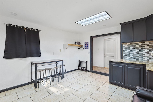 kitchen with light stone counters, baseboards, decorative backsplash, and light tile patterned floors
