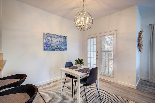 dining space featuring baseboards, a notable chandelier, french doors, and wood finished floors