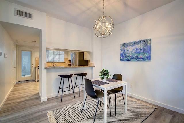 dining area with baseboards, a chandelier, wood finished floors, and visible vents