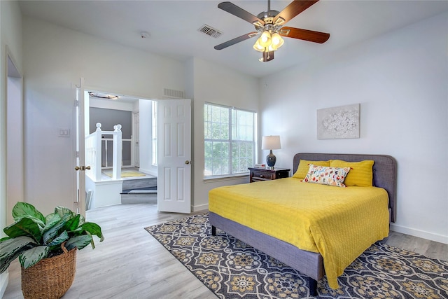 bedroom with wood finished floors, visible vents, a ceiling fan, and baseboards