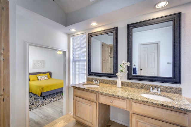 ensuite bathroom featuring ensuite bath, wood finished floors, a sink, and double vanity