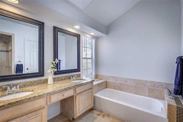 bathroom with a tile shower, double vanity, a garden tub, and a sink