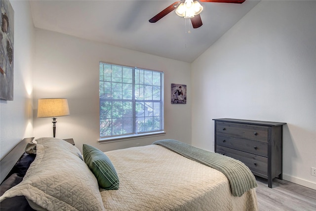bedroom with vaulted ceiling, light wood finished floors, baseboards, and a ceiling fan