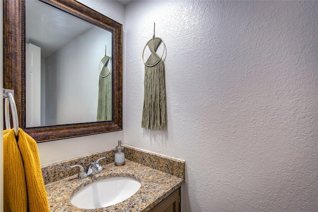 bathroom with a textured wall and vanity