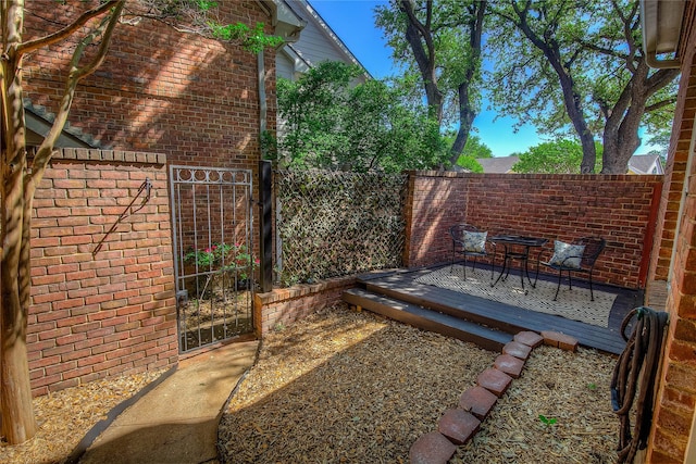 view of patio / terrace with a gate, a wooden deck, and fence
