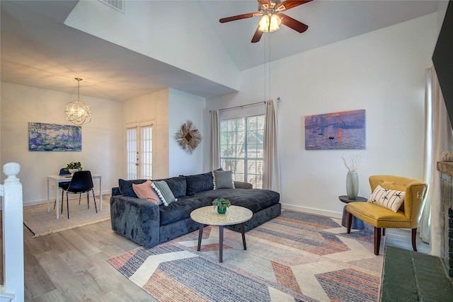 living room with light wood-style flooring, visible vents, a ceiling fan, and baseboards