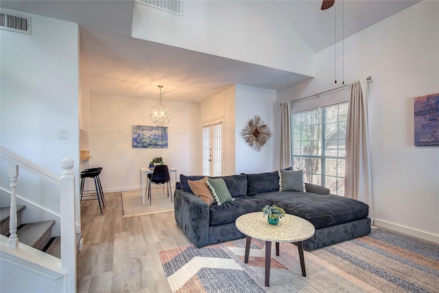 living area with light wood-style floors, stairway, visible vents, and a notable chandelier