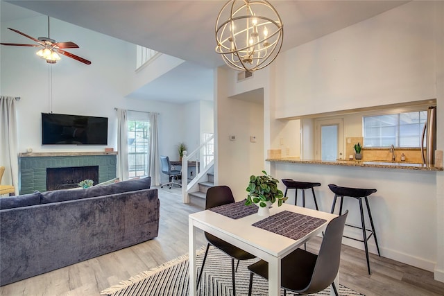 dining area with visible vents, a brick fireplace, wood finished floors, and a high ceiling
