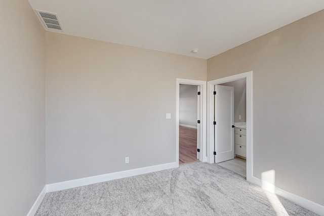 unfurnished bedroom featuring baseboards, visible vents, and light colored carpet