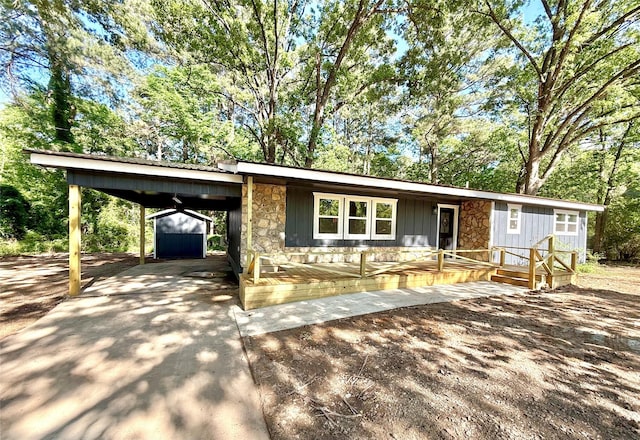369 County Road 2119, Quitman, TX 75783 - view of front of home with driveway, a carport, stone siding, board and batten siding, and a storage unit