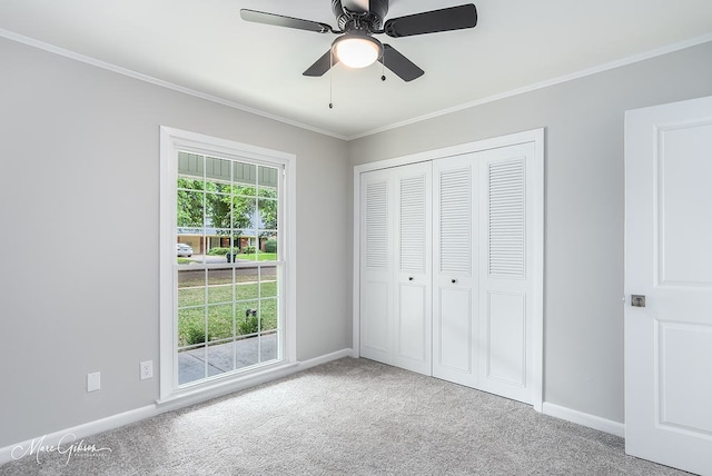unfurnished bedroom with ornamental molding, a closet, baseboards, carpet flooring, and ceiling fan