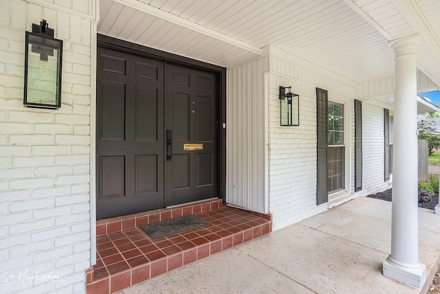 doorway to property with brick siding and a porch