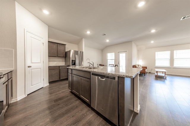 kitchen with a sink, an island with sink, appliances with stainless steel finishes, and dark wood-style flooring