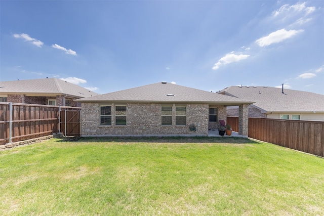 rear view of house with a fenced backyard, brick siding, a patio area, a lawn, and a shingled roof