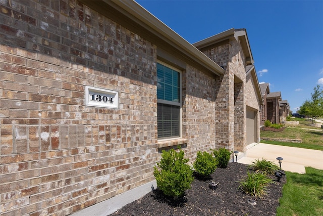 view of side of property featuring brick siding, driveway, and a garage