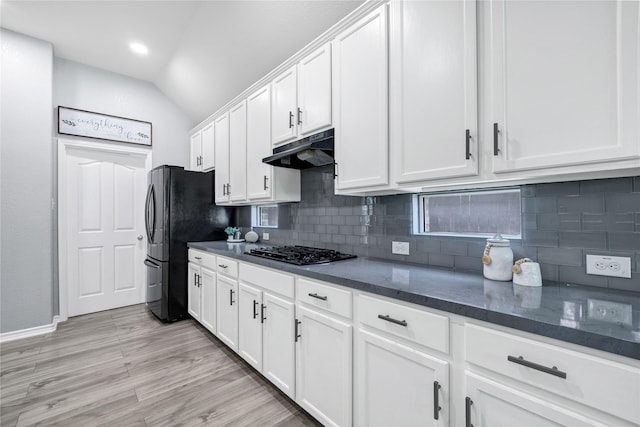 kitchen with white cabinets, black appliances, backsplash, lofted ceiling, and under cabinet range hood