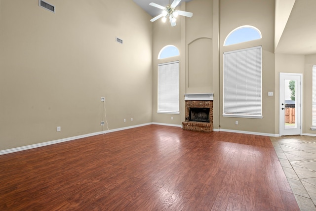 unfurnished living room featuring visible vents, a ceiling fan, baseboards, a fireplace, and high vaulted ceiling