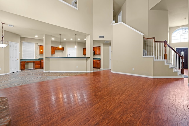 unfurnished living room featuring a chandelier, wood finished floors, a high ceiling, and baseboards