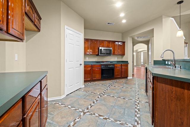 kitchen featuring oven, arched walkways, a sink, stainless steel microwave, and baseboards