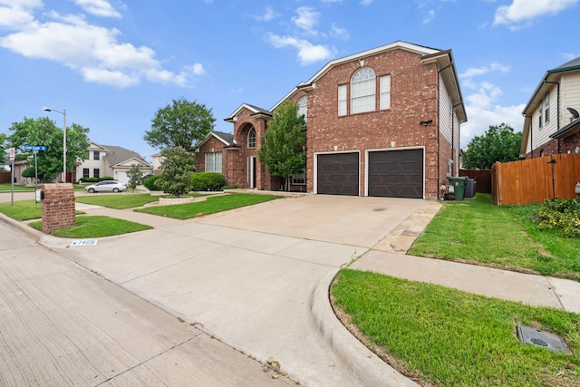 traditional-style home featuring a front lawn, concrete driveway, fence, a garage, and brick siding