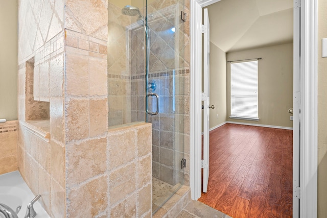 full bathroom with a bath, wood finished floors, a shower stall, and lofted ceiling