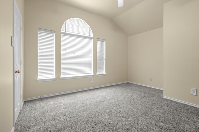 carpeted spare room featuring lofted ceiling, a ceiling fan, baseboards, and a healthy amount of sunlight