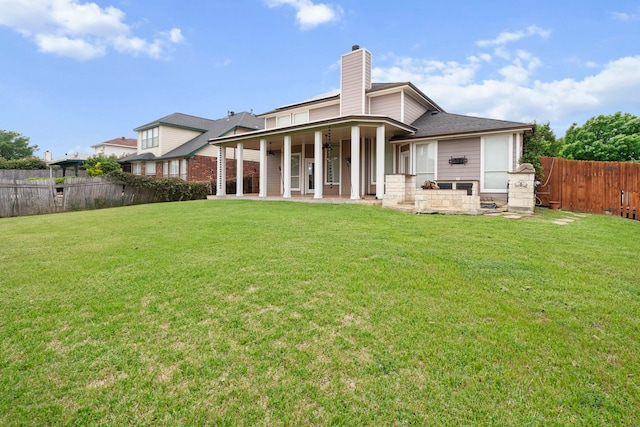 back of house featuring a fenced backyard, a yard, a chimney, and a patio