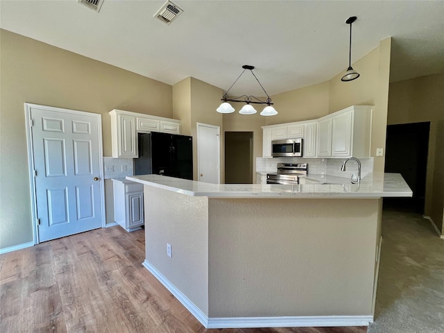 525 Reagan Ln, Burleson, TX 76028 - kitchen with white cabinets, visible vents, decorative backsplash, a peninsula, and appliances with stainless steel finishes
