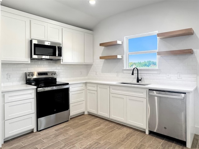 kitchen featuring open shelves, white cabinets, a sink, and appliances with stainless steel finishes