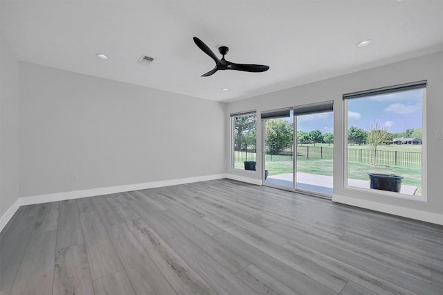 unfurnished room featuring baseboards, wood finished floors, visible vents, and a ceiling fan