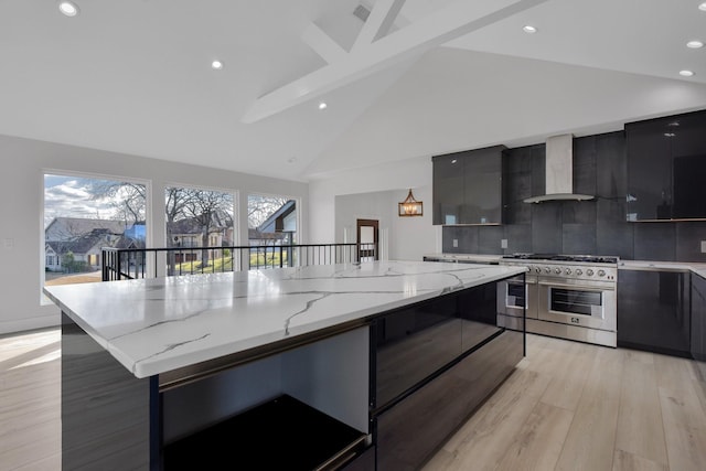 kitchen with light wood-type flooring, modern cabinets, high end range, and wall chimney range hood