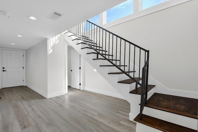 stairway featuring baseboards, wood finished floors, visible vents, and recessed lighting