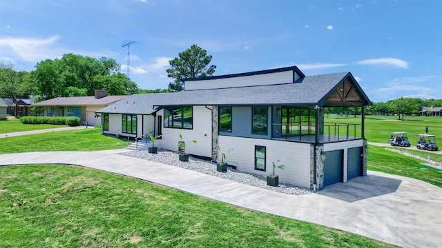 view of front facade with an attached garage, a shingled roof, a front yard, and concrete driveway